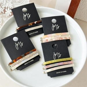 Detail view of 3-piece acetate hair clips set with marble patterns on white ceramic tray