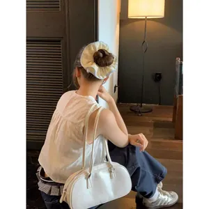Dettaglio dell'elastico per capelli bianco oversize abbinato a borsa in pelle bianca