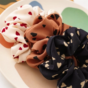 Dettaglio di tre elastici per capelli in tessuto con cuori in un piatto decorativo