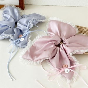 Detail of satin scrunchies with white lace edges, ribbon bows and buttons in light blue and pink