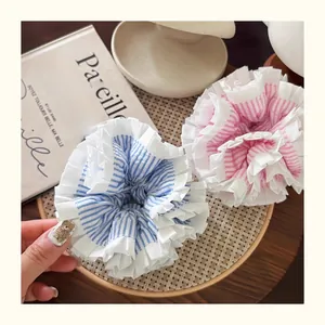 Close-up of blue and pink striped ruffle scrunchies with white floral lace edges