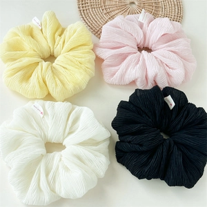 Close-up of four oversized chiffon scrunchies in yellow pink ivory and black colors