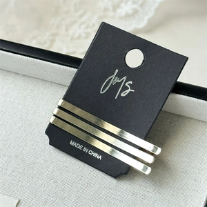 Close-up of three metallic gold hair pins on a display card over a lace jewelry box