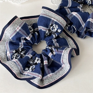 Detailed macro view of blue checkered scrunchie with delicate floral embroidery patterns