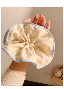 Vista dettagliata dell'elastico scrunchie crema al polso con stampe floreali blu