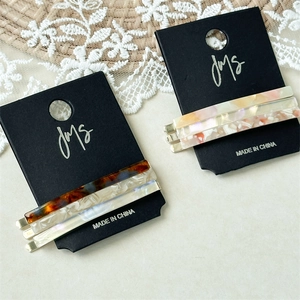Close-up of three acetate hair clips in tortoise, marble, and pink patterns on display