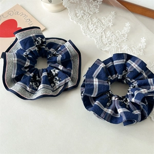Detailed close-up of two blue checkered scrunchies with fine floral embroidery