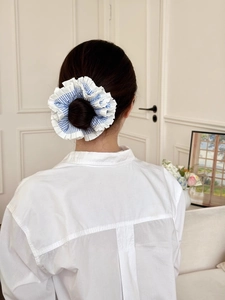 Detail view of a blue and white striped oversized scrunchie with layered ruffles on hair