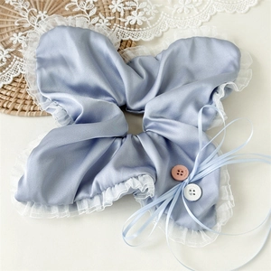 Detail of blue satin and lace scrunchie with decorative buttons and ribbon ties