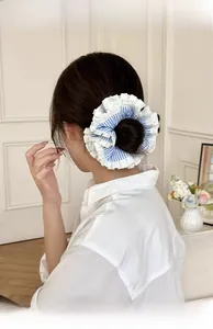 Detail of layered blue striped scrunchie with white ruffle trim on a model's hair