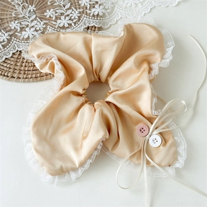 Detail of satin scrunchie with white lace edges, pink buttons and long ribbon accents
