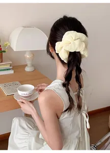 Close-up of a cream pleated oversized hair scrunchie with soft chiffon texture