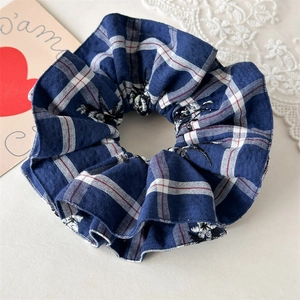 Detail of navy blue plaid scrunchie with floral embroidery and high-elastic pleated fabric