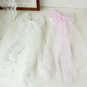 Détail de nœuds de mariée en résille avec perles et longs rubans de tulle blancs et roses