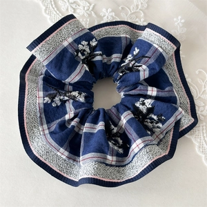Detail of navy blue plaid hair scrunchie with floral embroidery and pink edge stitching