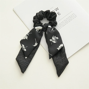 Macro detail of a black polyester scrunchie with floral ribbons on a magazine