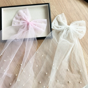 Détail de pinces à cheveux noeud en tulle rose et blanc avec perles et rubans flottants