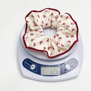 Gros plan d'un chouchou blanc à nœuds rouges sur une balance pesant 12,6 g