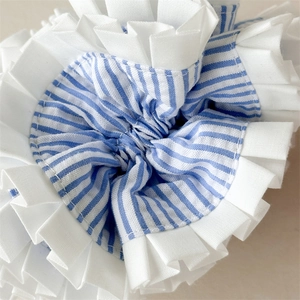 Detail shot of blue and white striped fabric scrunchie with white ruffled lace edging