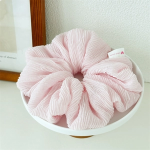 Close-up of pink ruched hair scrunchie with handmade label on white ceramic tray