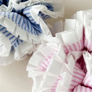 Close-up detail of blue and pink striped scrunchies with white pleated ruffled edges