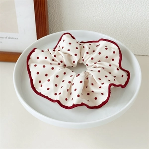 Vue détaillée du chouchou à pois avec bords festonnés rouges sur un plateau blanc