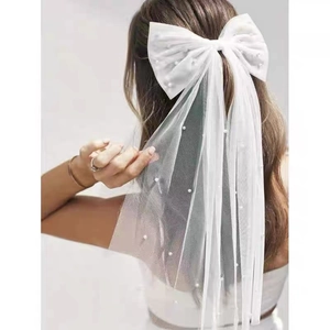 Détail de nœud en satin blanc avec voile en tulle et perles éparses pour coiffure de mariée