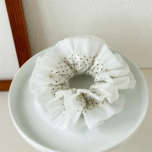 Detail of white lace hair scrunchie with black polka dots and tiered ruffle layers