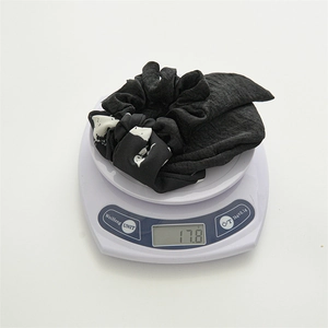 Polyester fabric hair scrunchie with bow tie showing weight of 17.8g on scale