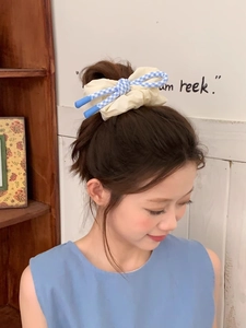 Détail d'un chouchou à nœud à carreaux bleu et blanc avec texture en tissu bouffant