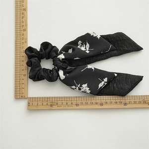 Polyester fabric scrunchie with long bow ribbon and floral pattern on white background