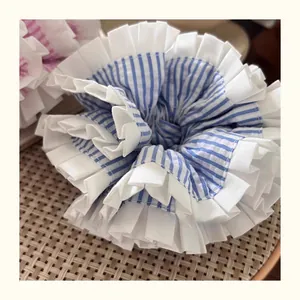 Detail of blue and white striped scrunchie with lace edges on a woven tray