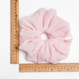 Macro detail of a soft pink bubble scrunchie with handmade label and 15cm size measurement