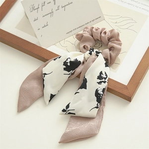 Detail of dusty pink satin scrunchie with elegant black and white floral print streamers