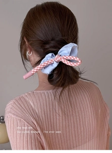 Détail d'un chouchou à nœud écossais bleu et rose porté sur un chignon volumineux
