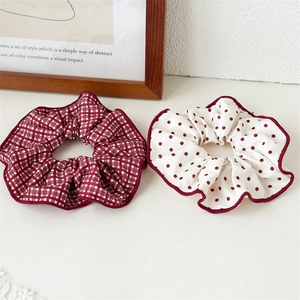 Gros plan de chouchous en satin à carreaux rouges et à pois blancs avec bords bordeaux