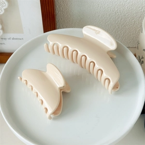 Close-up of cream-colored glossy fan-shaped hair claws in different sizes on a tray