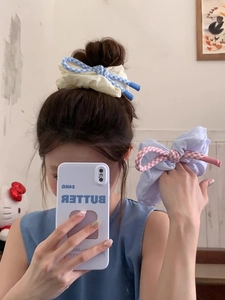 Détail de chouchous à carreaux roses et bleus avec nœud portés en chignon et au poignet