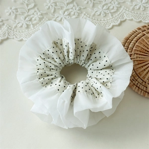 Detail of white lace and black polka dot chiffon layered scrunchie on rustic surface