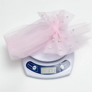 Pince à cheveux nœud en tulle rose avec perles sur balance affichant 17,3g de légèreté