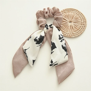 Detail of elegant satin scrunchie with floral ribbons on a cream background