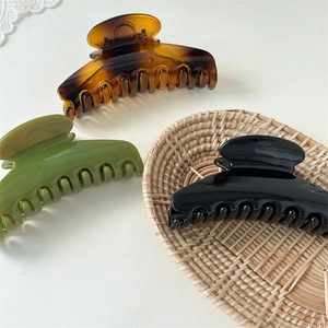 Detailed view of large fan-shaped hair claws in amber, olive green, and glossy black