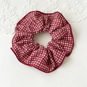 Vue détaillée d'un chouchou en coton à carreaux rouges et blancs avec texture froissée