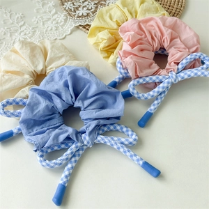 Détail du chouchou à carreaux bleus et roses avec nœud et texture de tissu doux