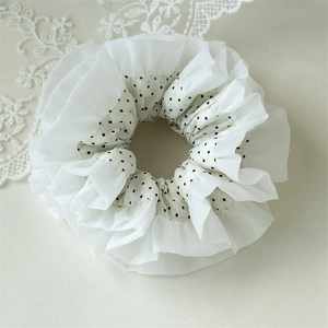 Close-up of white oversized scrunchie with black polka dots and layered lace edge