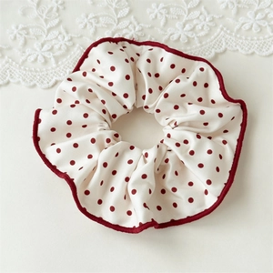 Détail d'un chouchou en satin crème à pois rouges et bords surjetés rouges élégants