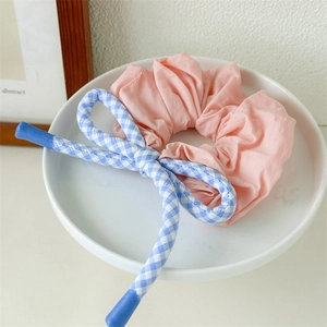 Chouchou rose à volants avec ruban à carreaux bleus dans un bol blanc décoratif