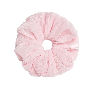 Pink fabric scrunchie with handmade label and soft texture on white background