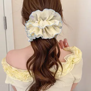 Detailed close-up of a large yellow floral chiffon scrunchie with blue ruffled edges