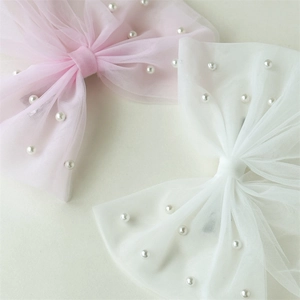 Détail de nœuds à cheveux en résille rose et blanc ornés de perles élégantes
